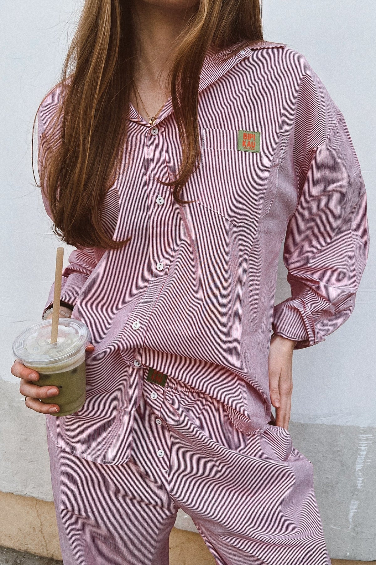 Soleil Set de Bipikau: conjunto de camisa oversize y pantalón fluido de rayas rosas, con un café en la mano