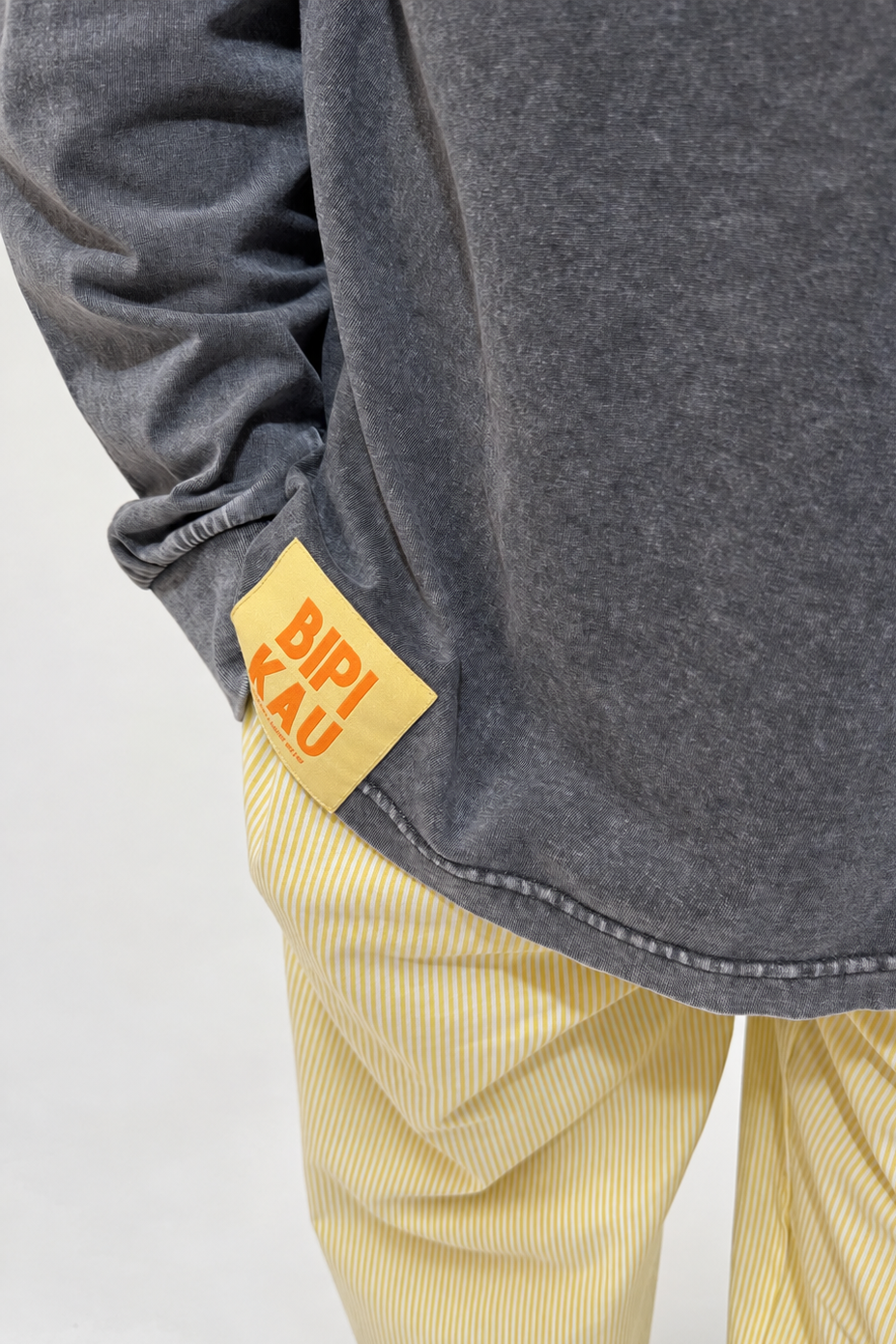 Detalle de la etiqueta naranja de Bipikau en el bajo de la Cactus Tee Grey, algodón gris lavado