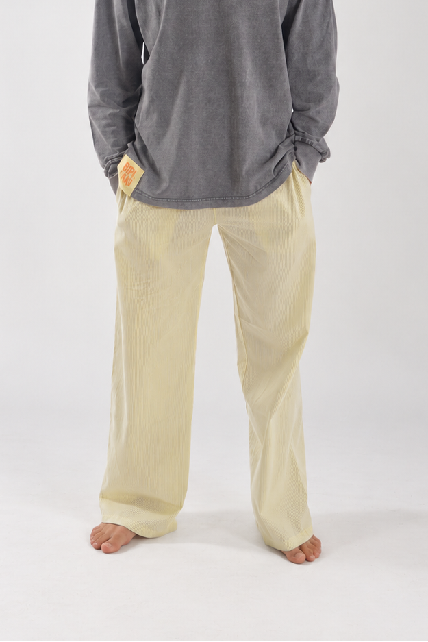 Modelo de frente con los Sunset Pants Yellow de Bipikau, pantalón ancho amarillo claro, y camiseta gris