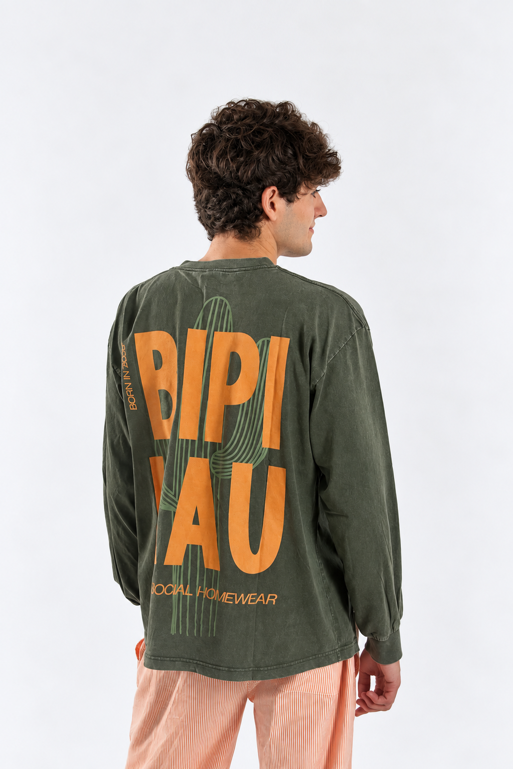 Modelo de tres cuartos de espaldas con la Cactus Tee Khaki de Bipikau y el logo naranja en la espalda