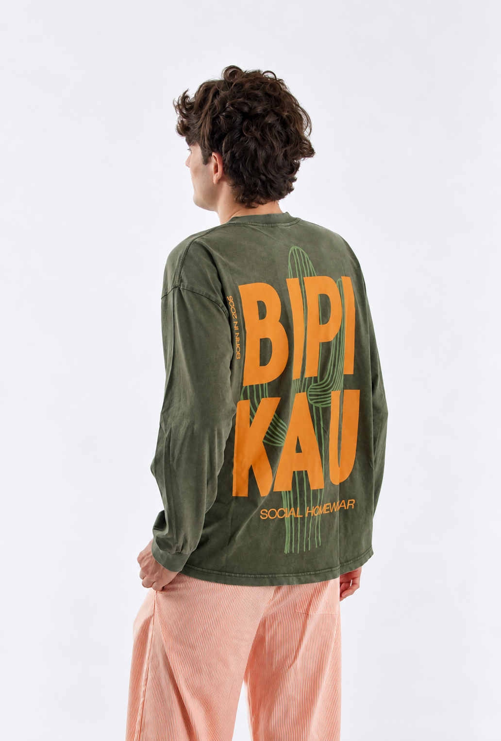 Modelo de espaldas con la Cactus Tee Khaki de Bipikau y pantalón de rayas naranjas