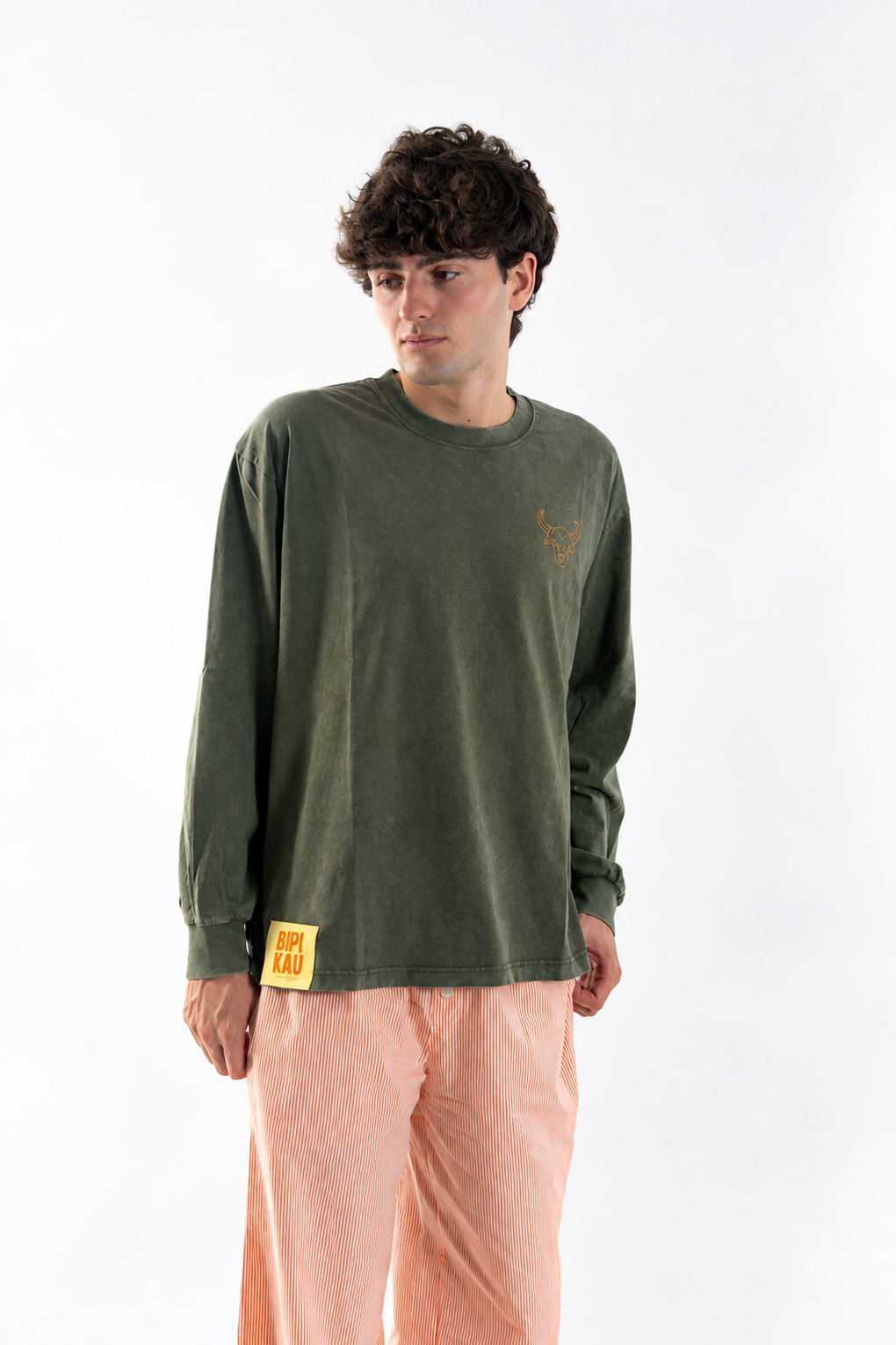 Modelo de frente con la Cactus Tee Khaki de Bipikau, camiseta oversize verde caqui de algodón, y pantalón de rayas naranjas
