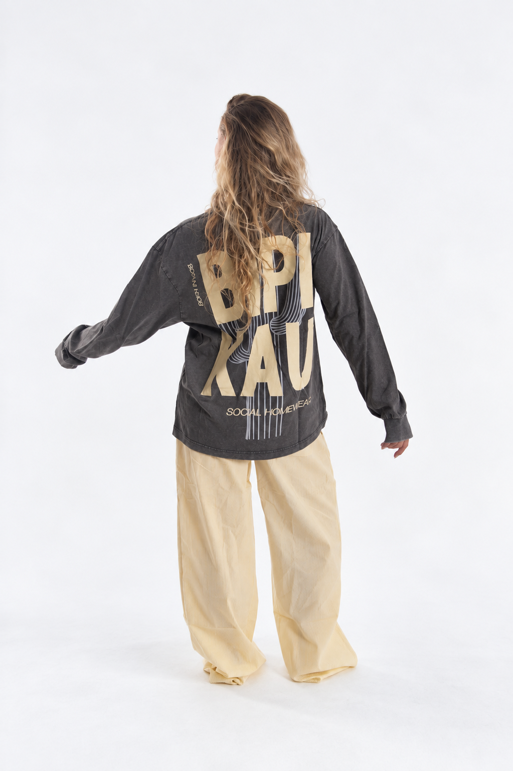Modelo de espaldas con la Cactus Tee Grey de Bipikau, logo grande en la espalda, y pantalón ancho amarillo claro