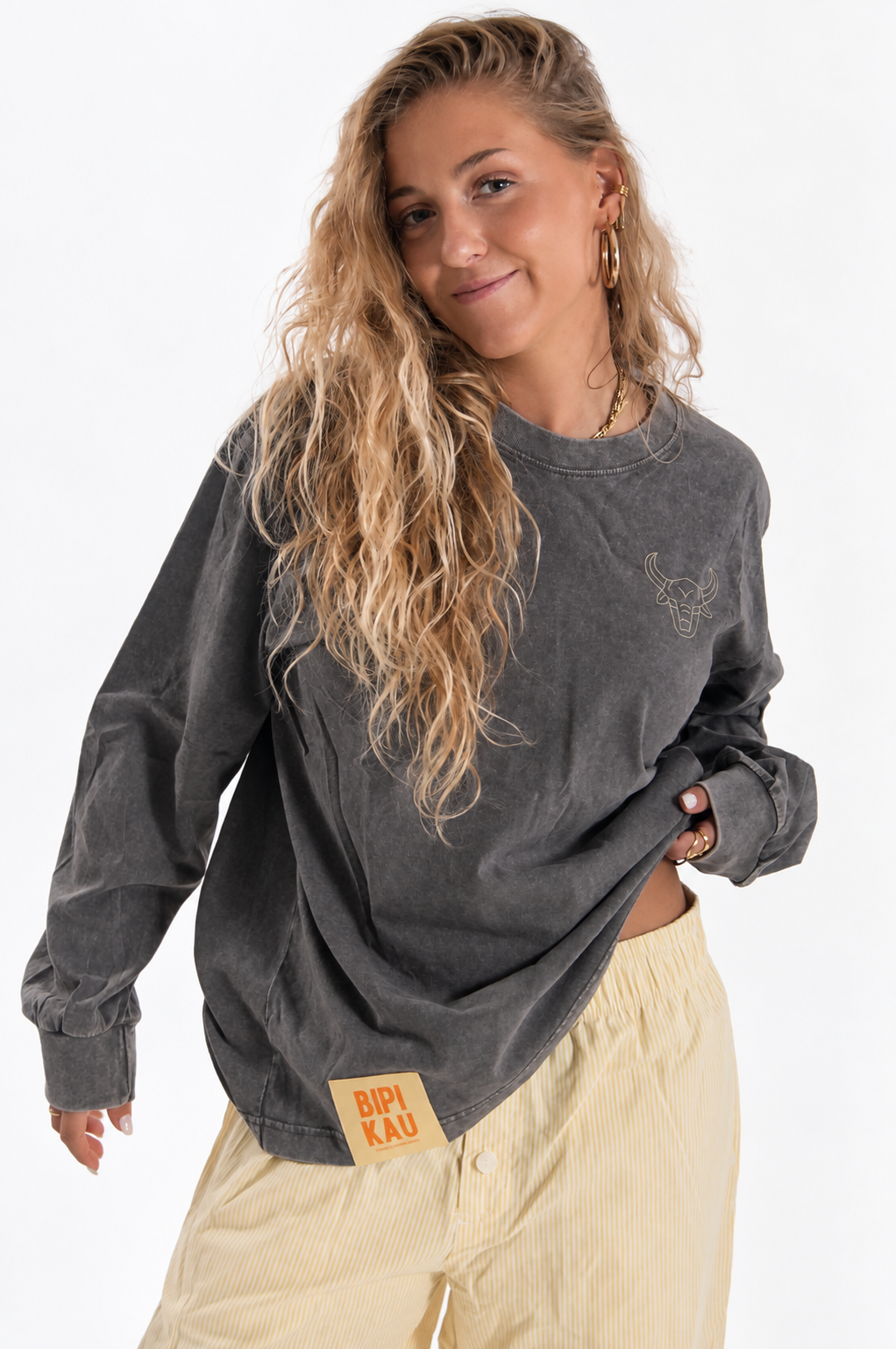Modelo sonriendo con la Cactus Tee Grey de Bipikau, camiseta oversize gris lavado, y pantalón de rayas amarillo claro