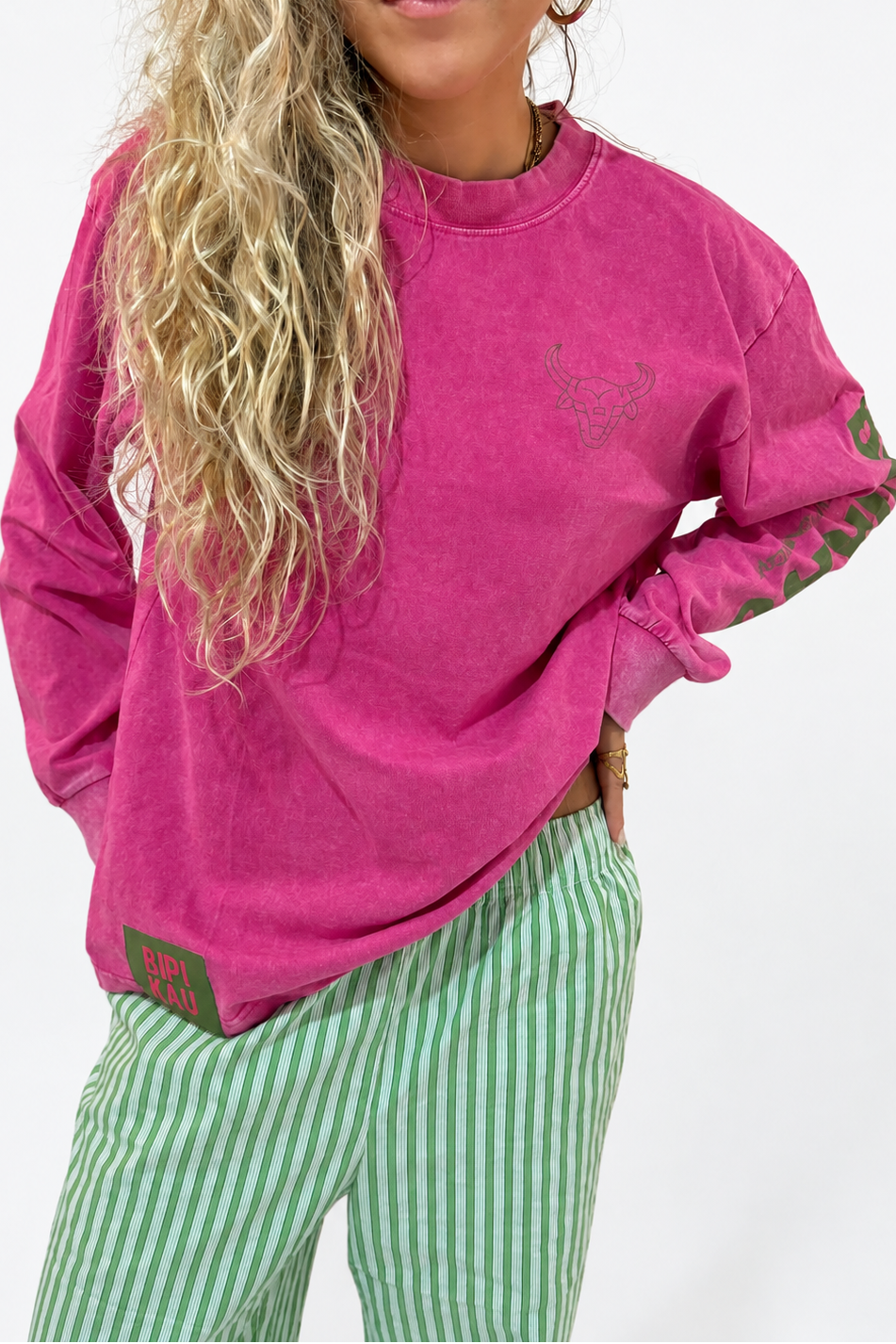 Modelo de frente con la Hibiscus Tee de Bipikau, camiseta oversize fucsia de algodón, y pantalón de rayas verdes