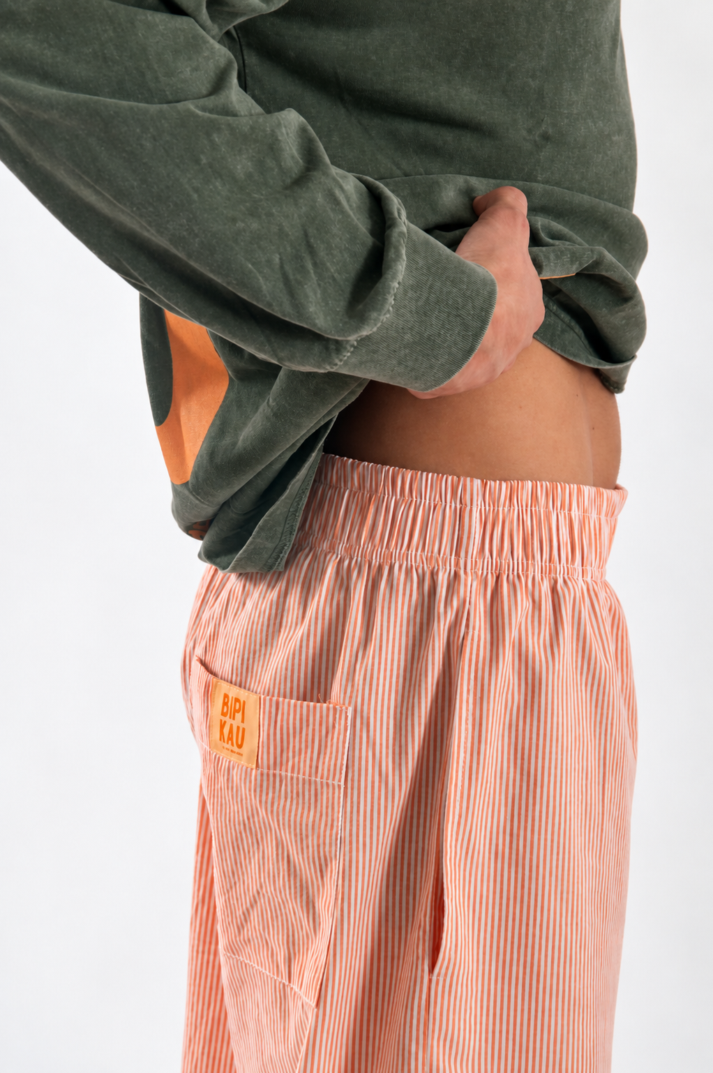 Detalle lateral de los Sunset Pants Orange de Bipikau: cintura elástica y bolsillo con etiqueta